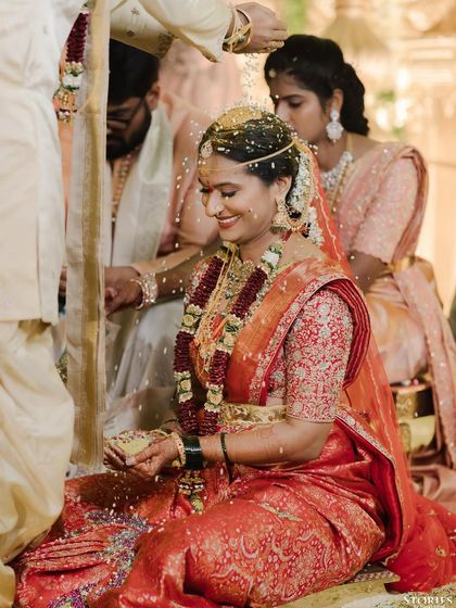 A candid moment of joy during a South Indian wedding ritual, as the bride Sravanthi is showered with sacred rice.