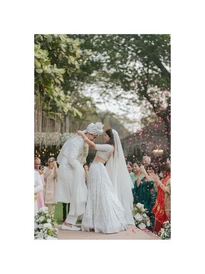Pure, unscripted joy. We live for these candid moments, like this first kiss as husband and wife, showered in petals by loved ones. It’s the raw, unfiltered emotion that truly tells your love story.