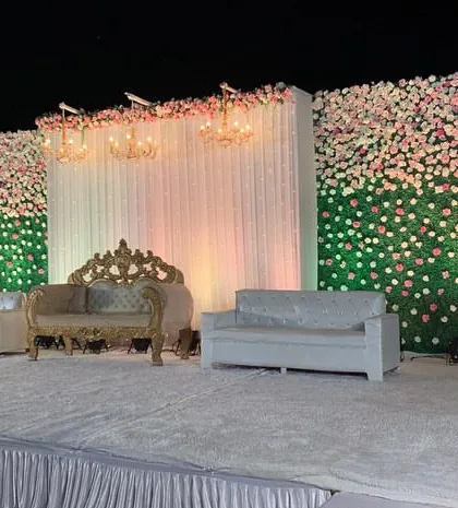 An angled view of the green and white flower wall stage. This perspective highlights the clean lines and symmetrical design, perfect for formal wedding receptions.