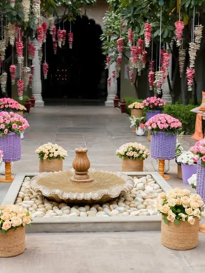 A beautiful courtyard decorated with hanging floral arrangements and colorful flower pots around a central fountain.