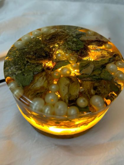 The round floral lamp, lit up to show its beautiful glow. This piece makes a wonderful bedside lamp or decorative accent for any room.