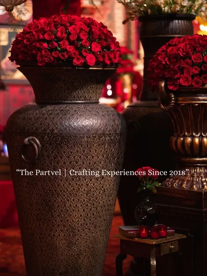 Crafting experiences since 2018. This image, with its rich red roses and antique-style urns, represents our commitment to creating timeless and luxurious event decor.