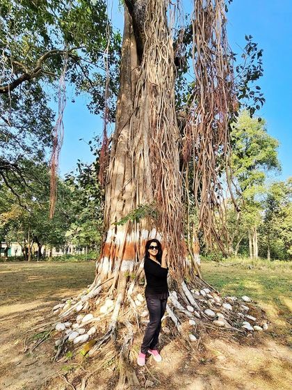 Standing grounded by a magnificent banyan tree. A simple all-black outfit allows the natural surroundings to take center stage.