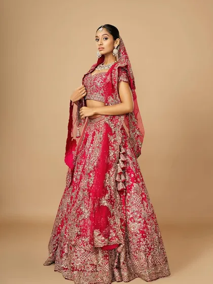 A full-length shot of a bride in a magnificent red lehenga. The makeup is designed to be both beautiful up close and striking from afar, ensuring she looks perfect throughout her wedding day.