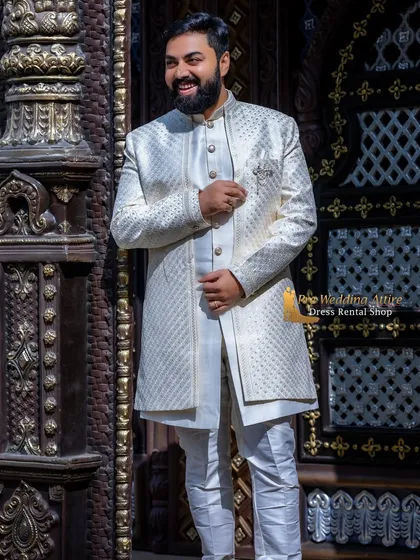 I provide a range of outfits for grooms, including this elegant off-white textured sherwani. It's designed to be sharp and sophisticated, pairing well with both traditional lehengas and western gowns for a complete couple's look.