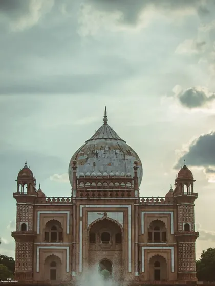 A dramatic shot of Safdarjung Tomb against a cloudy sky. The architecture is the hero here, and the moody sky adds a sense of history and grandeur to the monument.
