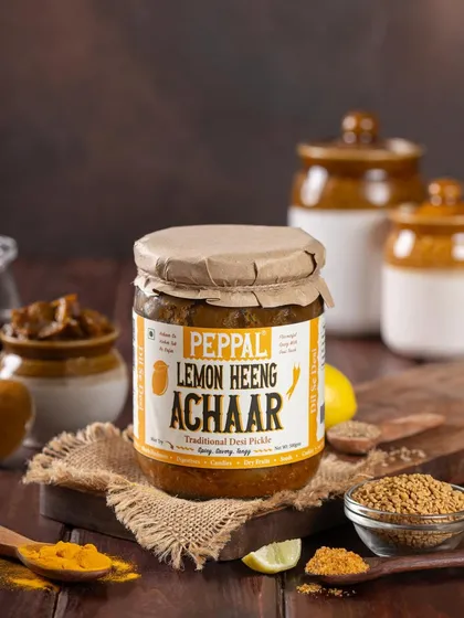 A styled shot of Peppal's Lemon Heeng Achaar, with key ingredients like lemon and spices displayed around it. This helps customers visualize the pickle's flavor profile.