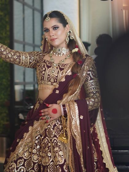 A full-length view of the bride, showing how the complete makeup and hair look comes together with her magnificent maroon and gold lehenga. My goal is to create a timeless and unforgettable bridal look.