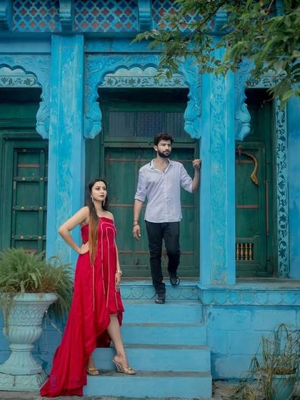 A fashionable pose on the steps of a vibrant blue and green building set. This location is perfect for creating colorful and stylish pre-wedding photos.