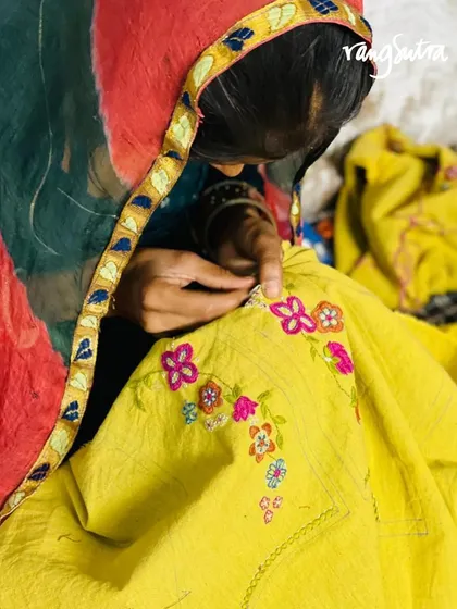 The pretty floral motifs of our Cheenth collection blouses are handcrafted using Pakka embroidery from Rajasthan. Here, an artisan works on a bright yellow blouse, adding colorful flowers along the neckline.