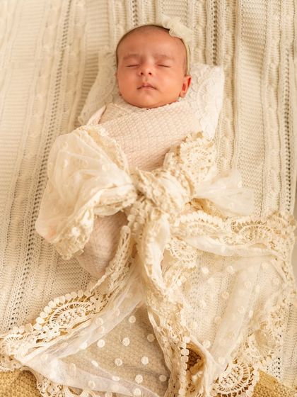 A newborn wrapped in a beautiful lace bow. This elegant and simple setup makes the baby look like the precious gift she is.