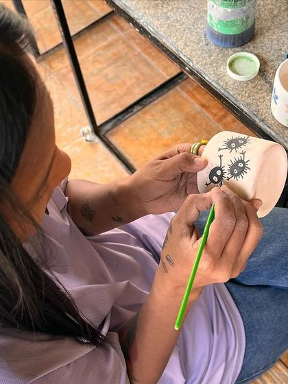 A student carefully painting a unique design onto her handmade mug. I love seeing their artistic ideas come to life.