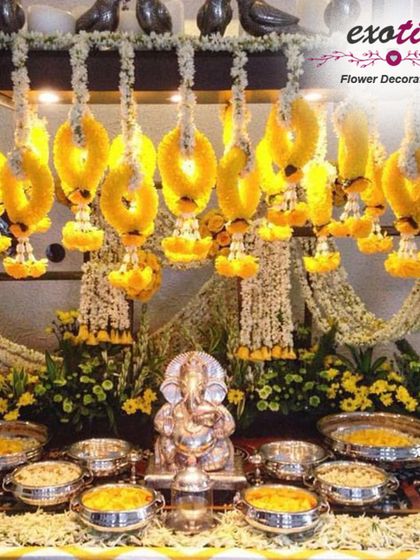 A traditional and ornate Ganpati setup. We used hanging garlands of yellow flowers and a base of fresh florals to create a golden, divine space for this silver Ganpati idol.