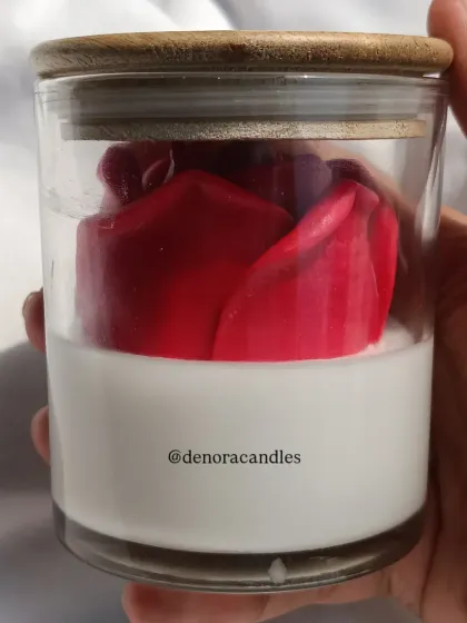 A hand-held view of the larger rose jar candle with a wooden lid.