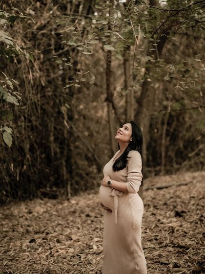 A beautiful solo portrait of the mom-to-be looking up into the canopy of the forest, a moment of peace and connection with nature.