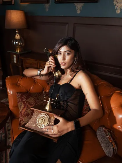 A storytelling image featuring a vintage rotary phone. The model's engagement with the prop adds a narrative layer to this classic, elegant fashion shoot.