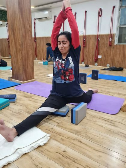 Another student practices the splits with the support of blocks under her hips. This modification makes the pose accessible and allows for a safe, deep stretch.