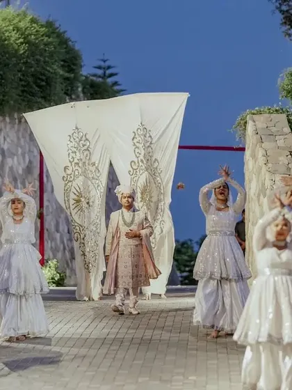 A grand, choreographed entrance for the groom, welcomed by dancers in white, setting a regal and theatrical tone for the wedding.