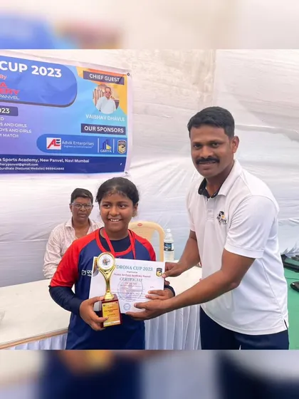 A young girl proudly holds her trophy and certificate. Events like the Drona Cup provide valuable competition experience for archers of all levels.