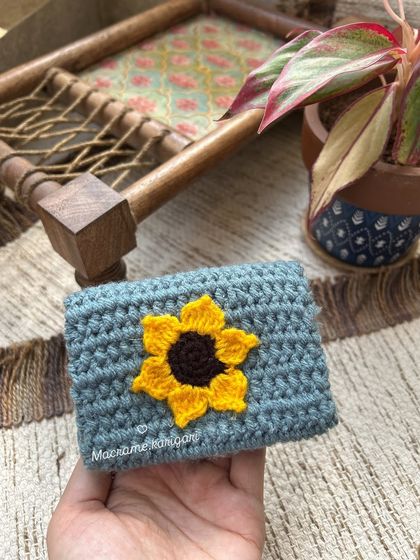 This mini wallet features a bright sunflower appliqué on a muted blue-grey background. It’s a little piece of sunshine you can carry with you every day.