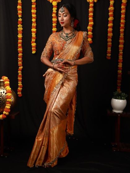 A full-length view of this stunning Deepavali festive look. The rich orange saree, intricate jewellery, and elegant pose capture the grace and beauty of the festival.