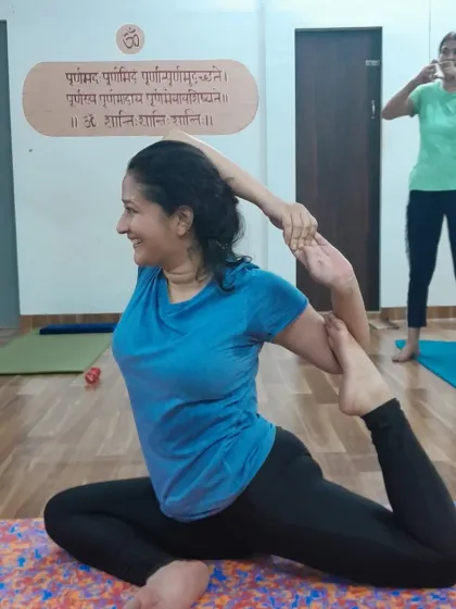 With a smile of serene focus, this student demonstrates her progress in this deep hip-opening posture.