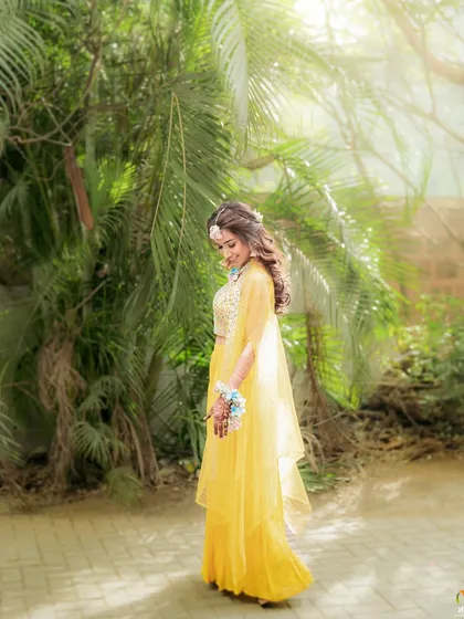The bride in her yellow lehenga, surrounded by sunlight. Our floral jewellery adds to the surreal, glowing effect of this beautiful photograph.