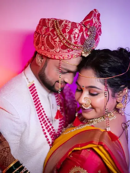 An intimate portrait of the couple against a colorful, lit background. Their traditional Marathi wedding attire shines in this creative shot.