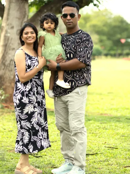 A lovely portrait of a young family of three standing together by a tree during their casual and natural outdoor photoshoot.