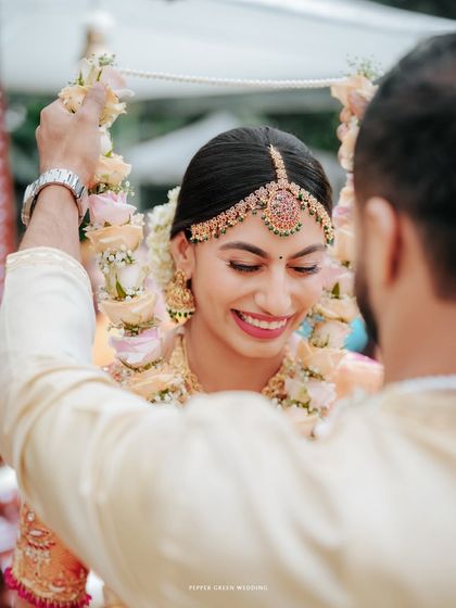 A close-up of the groom placing the garland on the bride, her joyful smile capturing the essence of the moment.