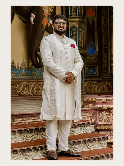 A classic portrait of the groom-to-be in a sophisticated off-white sherwani. His confident and happy demeanor is captured perfectly against an ornate backdrop.