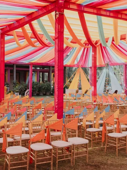 The vibrant, multi-colored draped ceiling and seating for a colorful Haldi celebration.