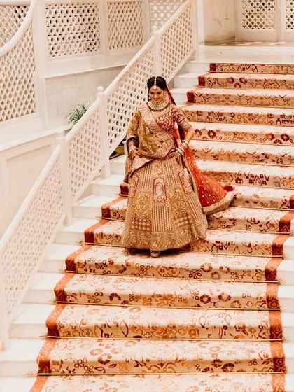 A grand staircase shot of the bride descending, her beautiful lehenga trailing behind her. A classic and elegant bridal portrait.