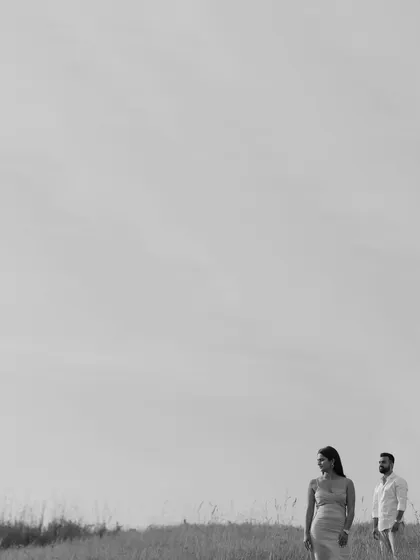 A minimalist black and white shot of the couple in a vast, open field, creating a feeling of solitude and togetherness against the wide sky.