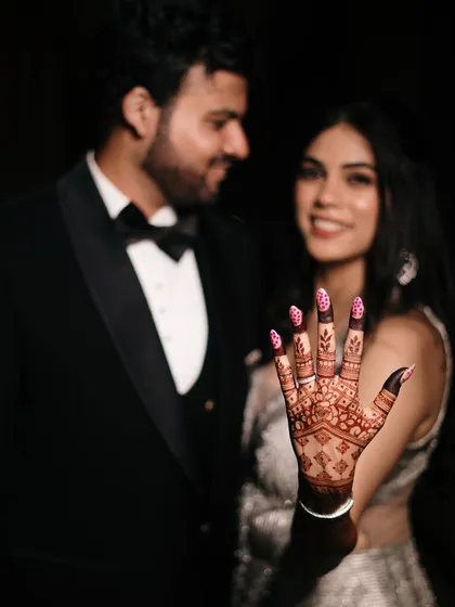 A creative shot focusing on the bride's intricate henna design, with the groom softly blurred in the background, symbolizing their union.