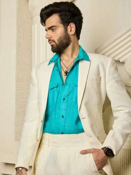 The crisp cream suit exudes understated luxury, while the turquoise button-down adds a refreshing contrast. This is elegance, redefined for warm days and stylish evenings.