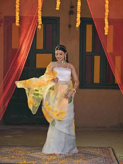 Another view of the artistic, hand-painted saree for a Haldi ceremony. The flowing fabric and delicate floral pattern make it a graceful and memorable outfit choice.