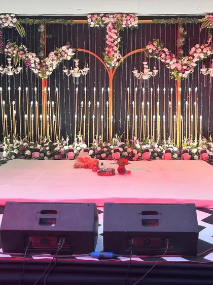 A stage ready for a night of performances. This setup includes a dance floor, professional speakers, and a beautifully decorated backdrop with floral arches and chandeliers.