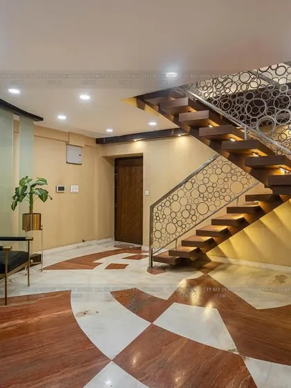 A stunning wooden staircase with an intricate laser-cut metal railing, set against a backdrop of red and white marble flooring.
