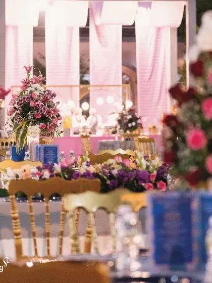 A view of the guest dining tables, beautifully decorated with floral centerpieces. The blurred foreground gives a sense of the lively and elegant atmosphere of the reception.