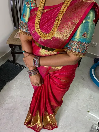 A perfectly draped pink Kanjivaram saree, showing how the pleats fall neatly. I ensure the drape is comfortable and looks great from every angle.