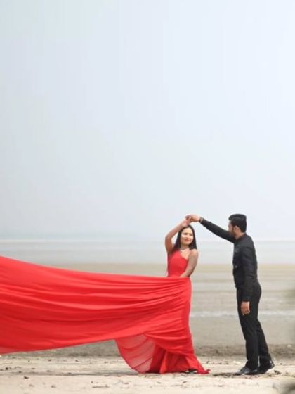 A playful dance on the beach. The movement of the red trail adds a sense of fun and freedom to this romantic pre-wedding moment.