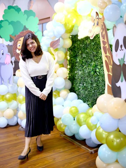 A guest poses in front of the vibrant jungle backdrop. The mix of a faux-grass wall and animal cutouts creates a fantastic photo opportunity.