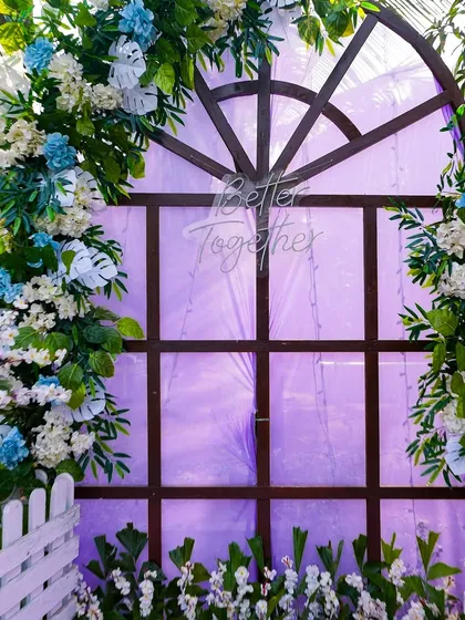 A close-up of the "Better Together" neon sign against a rustic window backdrop. This detail adds a modern and personal touch to the romantic, floral-adorned photo corner.