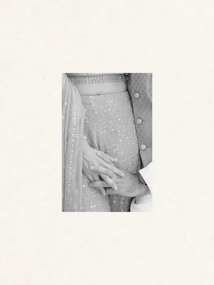 A minimalist, black and white detail shot of a couple holding hands.