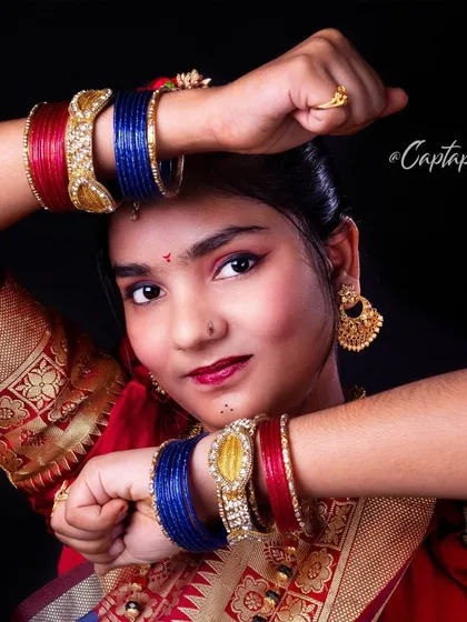 This portrait uses a dynamic pose, with the hands framing the face to draw attention to the colorful bangles and expressive eyes. It's a lively take on traditional portraiture.