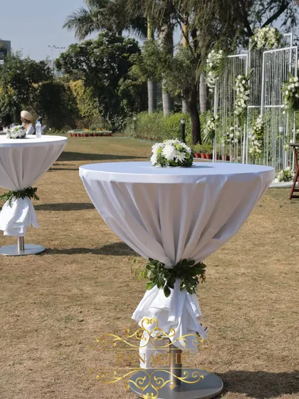 A close-up of the cocktail tables, draped in white linen with a simple green garland.