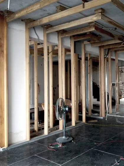 A construction photo from the Lucknow penthouse, showing the raw wooden framework for the partitions being installed against the black stone floor, revealing the skeleton of the design.