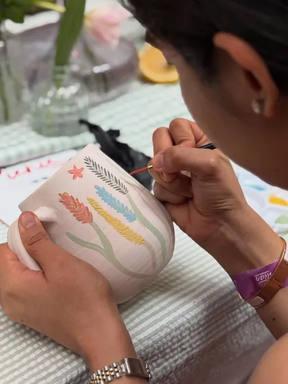 A guest paints a colorful wheat pattern onto their mug, bringing their own artistic flair to the piece.