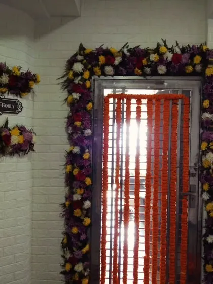 This is a main entrance decoration for a flat, featuring a full floral frame around the door and a matching arrangement over the nameplate. We used a mix of colorful flowers to create a festive and welcoming look.